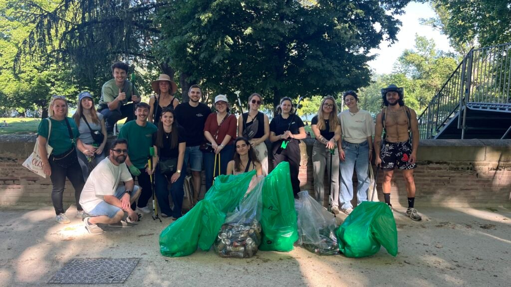 Groupe de participants à la cleanwalk rassemblés autour des sacs de déchets collectés à la Prairie des Filtres à Toulouse, à la fin de l’action de ramassage.